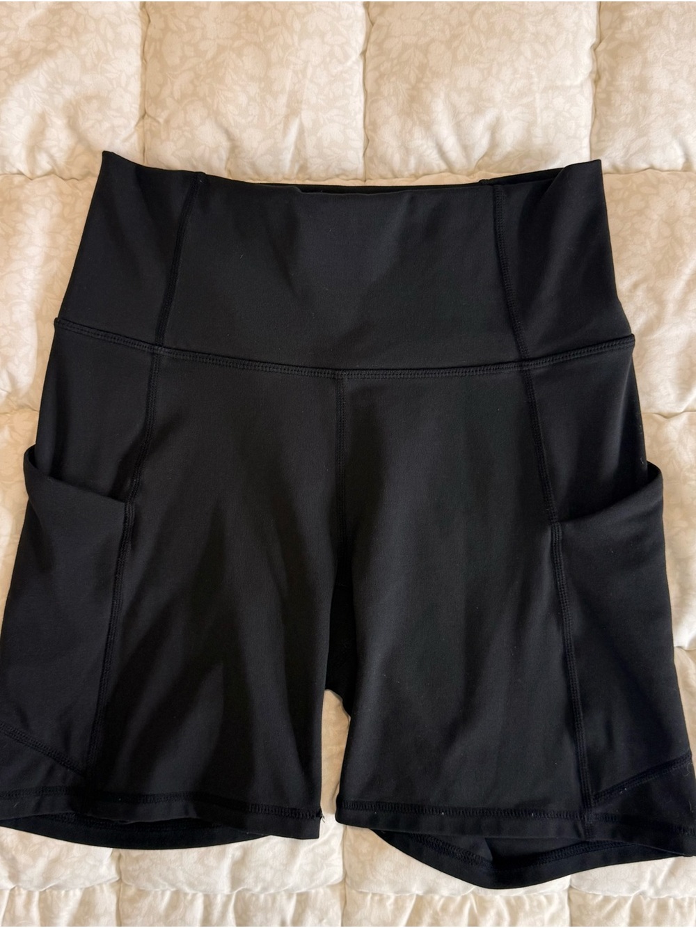 Fabletics high-waisted black athletic shorts featuring side pockets.